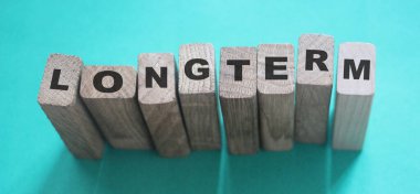 Cyan açık mavi arka planda tahta küplerle ilgili uzun vadeli bir kelime. Güvenilir iş uzun vadeli ilişki kavramı.