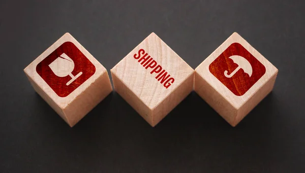 Shipping word and icons engraved on a wooden cubes, isolated on black background. Transport logistics business concept.