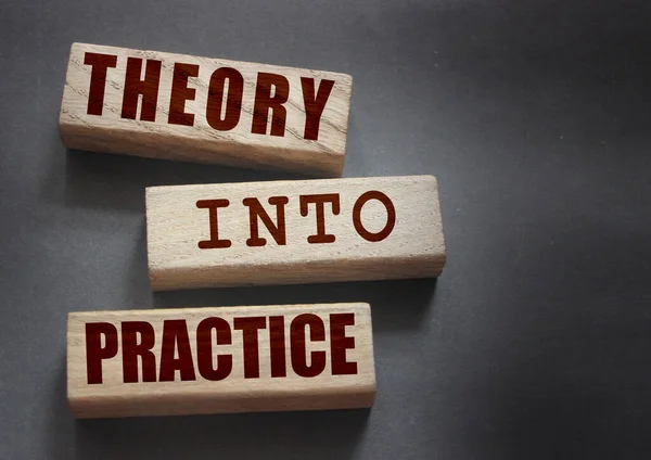 Theory into practice words written on wooden blocks. Education or business startup concept.