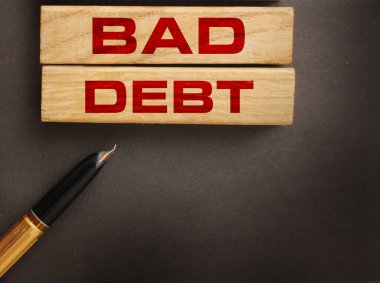 Tahta bloklar için kötü borç ve koyu gri arka planda lüks kalem. Finansal kayıplar ya da iş iflası kavramı .