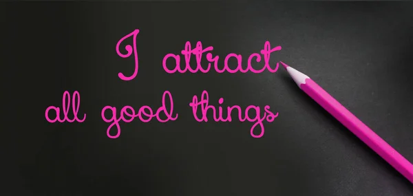 I attract all good things - positive affirmation words - handwriting on a black paper with a pink pencil. Law of attraction concept.