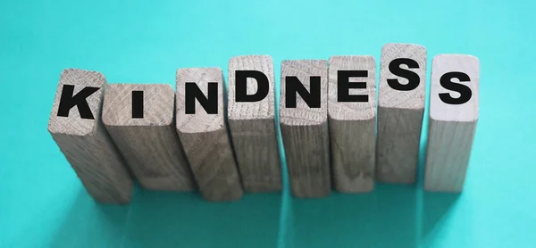 KINDNESS kelime ahşap yapı taşları ile yapılmış neon aquamarine arkaplan.