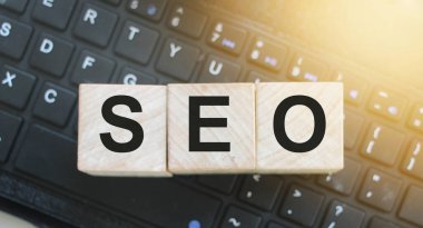 Arama motoru optimizasyonu için kısaltması SEO olan tahta küpleri bilgisayar klavyesine yerleştirildi. Çevrimiçi iş projeleri metin yazma kavramı.