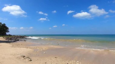 Koh Lanta adasının güzel beyaz kumsalı Phra Ae Long Beach, Krabi, Tayland. Kumlu kumsalın kayalık sahillerine küçük dalgalar sıçrayıp sıçrıyor. Gökyüzünde bulutlarla güneşli bir gün.