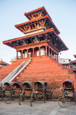 Kathmandu 'daki Durbar Meydanı' ndaki bir tapınağın önünde renkli ve geleneksel Nepal triportörleri. Gün doğumunda Durbar Meydanı 'nda boş ulaşım araçları.