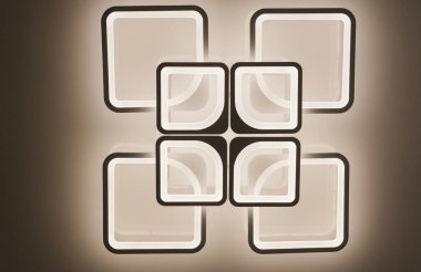  Odanın tavanında avize var. Yaratıcı avize tasarımı. Kare avize. Ilık ışık. Elektrik..