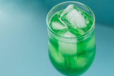 Mavi arka planda buzlu bir bardak yeşil kokteyl. Alkol için masa takımı. Şampanya ve şarap..