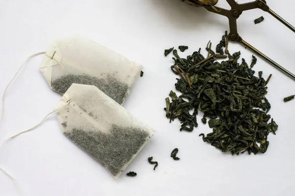 Çay poşetleri ve beyaz bir arka planda ufalanma. Farklı çay türleri. Yeşil ve siyah çay..
