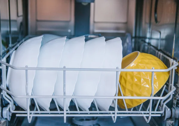 Dishwasher filled with dishes. The device and parts of the dishwasher.White and colored plates on the shelf.Repair.