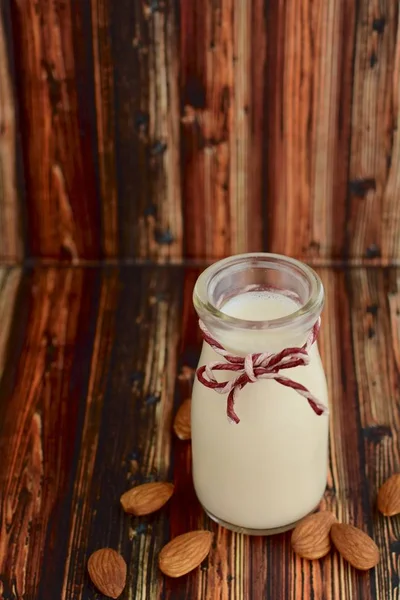 Homemade almond milk in a jar on wooden background