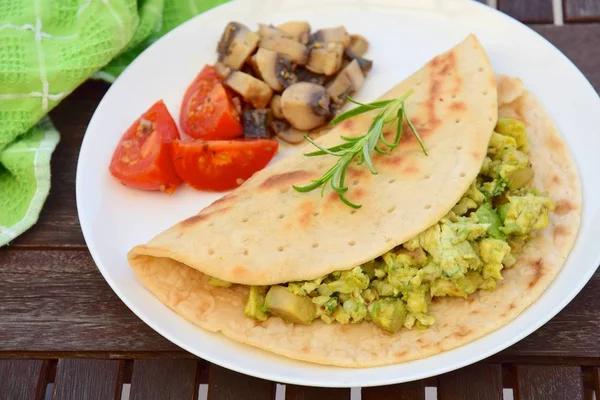 tortilla with scrambled egg avocado served with tomato and mushroom