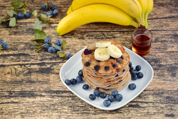 Healthy pancakes for breakfast made from buckwheat flour, almond milk, banana, blueberry and coconut flakes