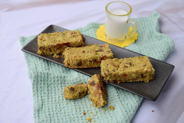 Yulaf, kibrit tozu, kibrit tozu, akçaağaç şurubu, kurt üzümü, kabak tohumu, ayçiçeği tohumu, hurma, Brezilya fıstığı ve susam tohumundan yapılmış yeşil çay barları. Sütle servis edilir.