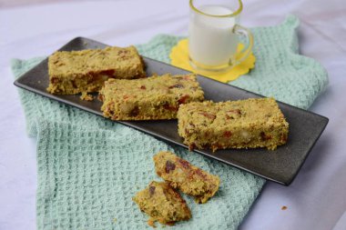 Yulaf, kibrit tozu, kibrit tozu, akçaağaç şurubu, kurt üzümü, kabak tohumu, ayçiçeği tohumu, hurma, Brezilya fıstığı ve susam tohumundan yapılmış yeşil çay barları. Sütle servis edilir.