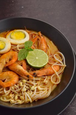 Karides, yumurta ve fasulye filizli Laksa şehriye çorbası. Limonlu ve nane yapraklı garnitür.