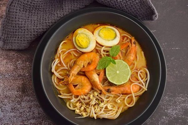 Karides, yumurta ve fasulye filizli Laksa şehriye çorbası. Limonlu ve nane yapraklı garnitür.