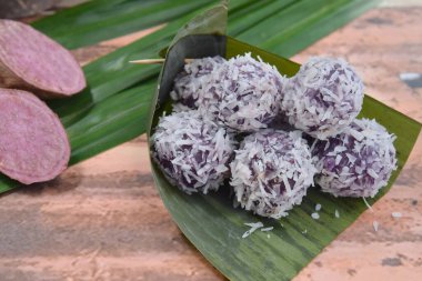 Klepon Ubi Ungu, Endonezya geleneksel tatlısı veya Jajanan Pasar. Kurutulmuş hindistan ceviziyle kaplı palmiye şekeriyle doldurulmuş mor, tatlı patates glutinous pirinç topları. Muz yaprağında servis edilir.