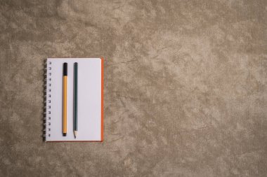 Kahverengi arka planda defter, kalem ve kalem. Üst görünüm ve boşluk kopyala. Metni girmek için boş alan 