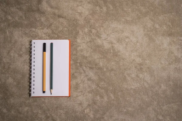 Kahverengi arka planda defter, kalem ve kalem. Üst görünüm ve boşluk kopyala. Metni girmek için boş alan 