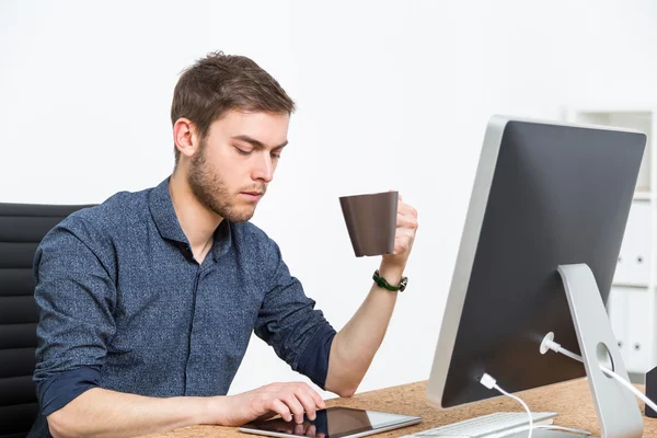 Young man with coffee in office — Stockfoto