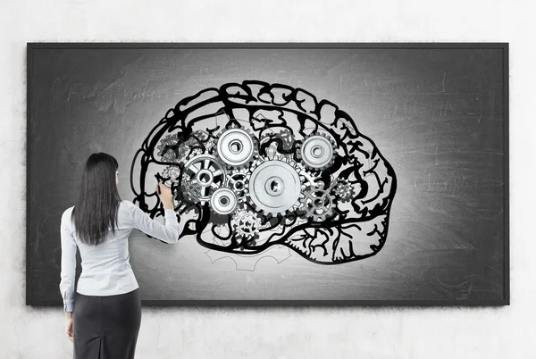 Woman working at brain sketch on blackboard — Stockfoto