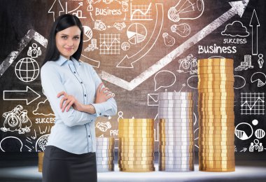 Siyah saçlı gülümseyen kadın dev sikke yığınları ve skeçler ile tahta ile odada duruyor. Bankacılık kavramı. Tonlu görüntü