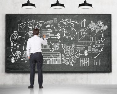 Young man drawing startup sketch on blackboard