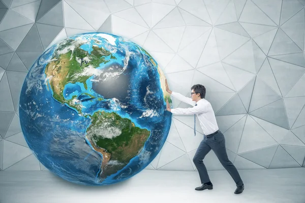 Man pushing Earth in concrete room with white floor — Stock Photo, Image