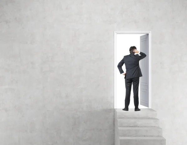 Businessman near open door in concrete wall with stairs — Stock Photo, Image