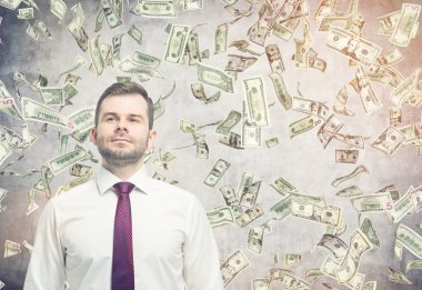 Odada dolar banknot yağmuru altında kendine güvenen işadamı