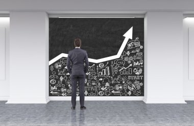 Lobide grafik ve iş ikonları okuyan takım elbiseli işadamı