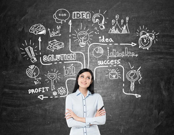 Girl with black hair near blackboard with business icon — Stock Photo, Image
