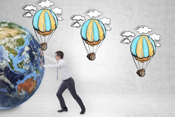 Бизнесмен толкает земной шар к эскизам воздушных шаров — стоковое фото