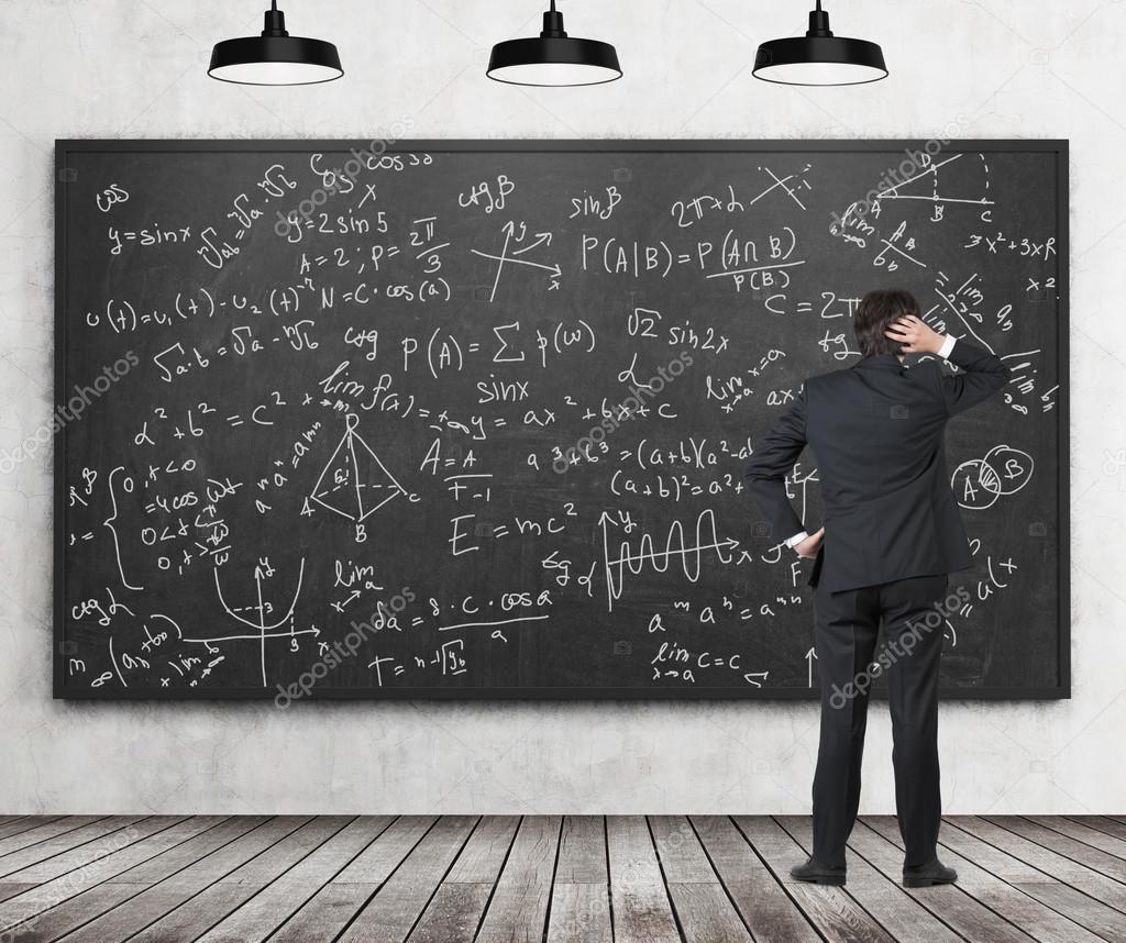 Man in suit looking at blackboard with formulas