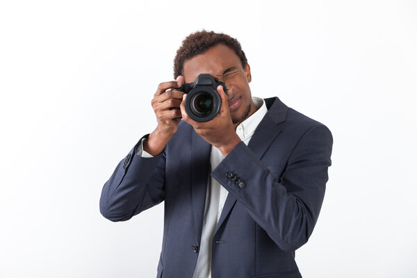 Businessman holding a camera and looking at the viewer and standing against white background. Concept of taking pictures