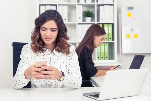 Två flickor i Office kontrollerar sina telefoner — Stockfoto