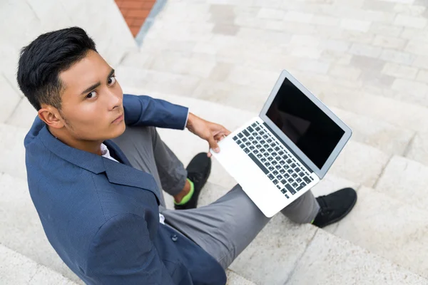 Asiatisk man med laptop på trappor — Stockfoto