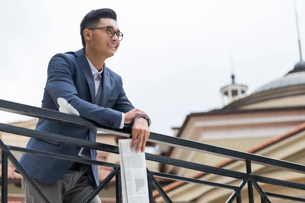 Asian businessman holding newspaper