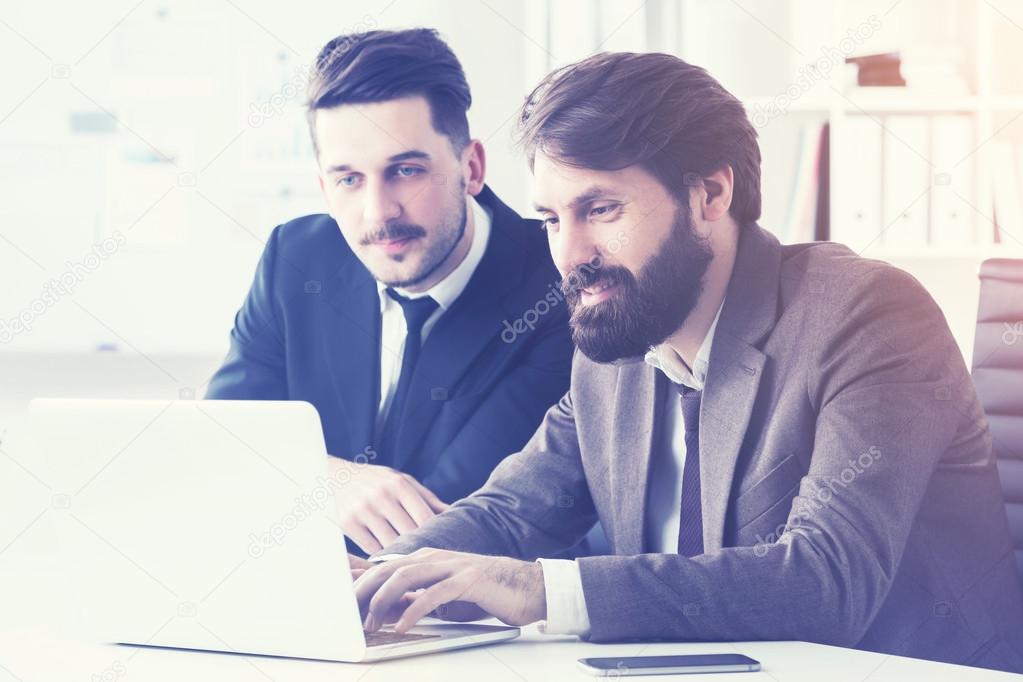 Businessmen discussing project and working on laptop