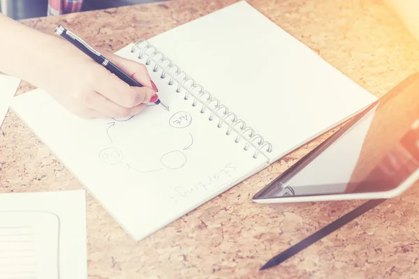 Woman hand drawing a scheme while she looks at tablet screen — Stockfoto