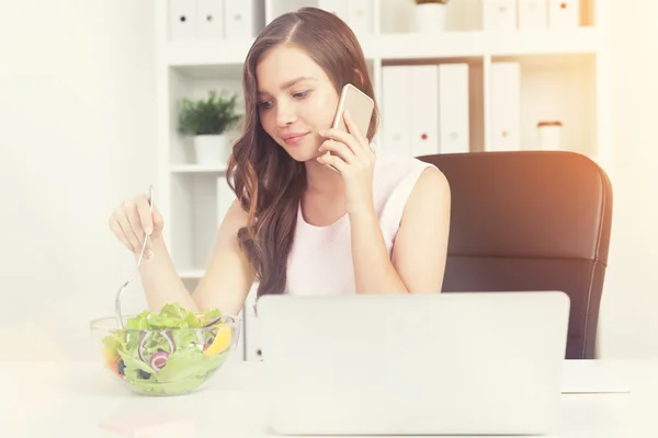 Женщина с ноутбуком ест салат в сунит-офисе — стоковое фото