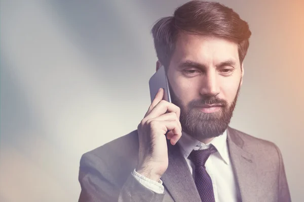 Bebaarde man in pak op telefoon — Stockfoto