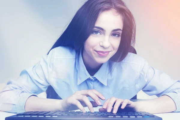 Atractiva mujer sonriente está utilizando el teclado — Foto de Stock