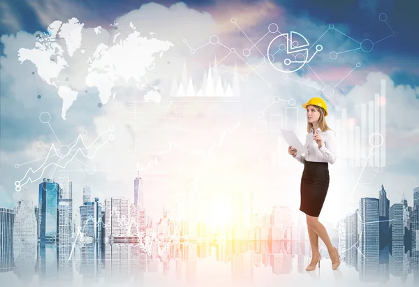 Woman in yellow hard hat and diagrams against cityscape — Φωτογραφία Αρχείου