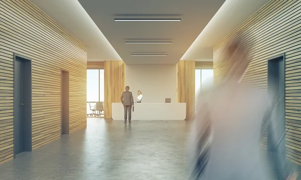 Resepsiyon sayacı ile güneşli ofis koridorunda insanlar — Stok fotoğraf