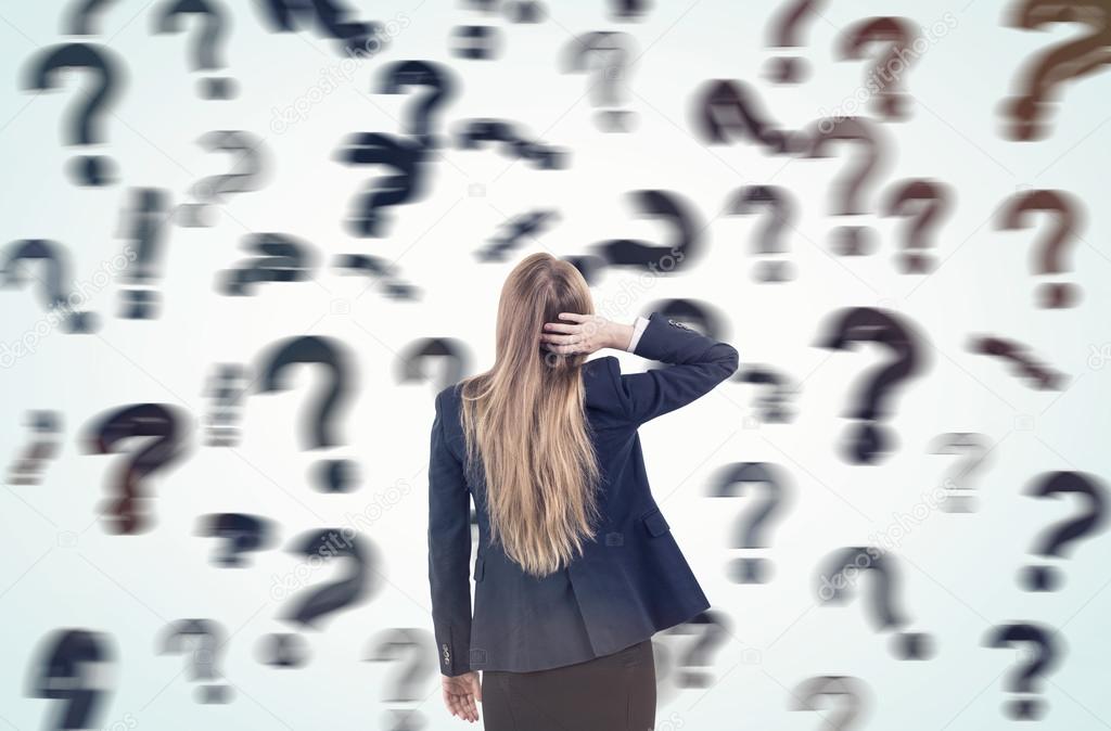Woman scratching head and looking at blurred question marks