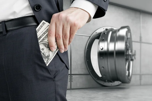 Man putting money into pocket near vault — Stock Photo, Image