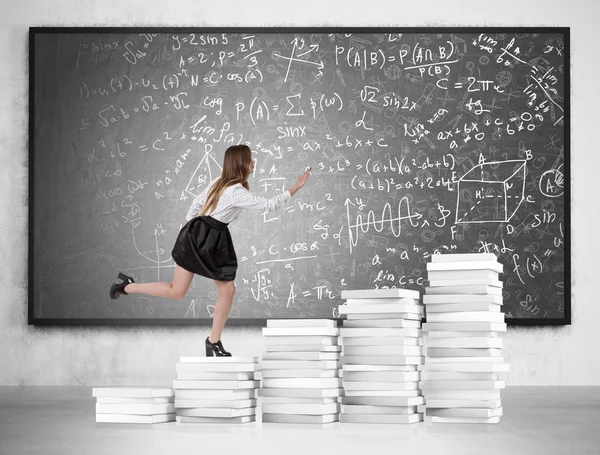 Woman running up paper stack stairs — Stockfoto