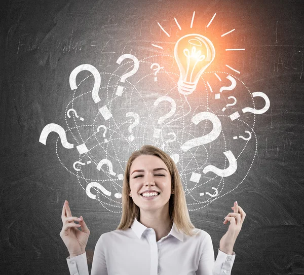 Woman with crossed fingers and light bulb with question marks — Stock Photo, Image