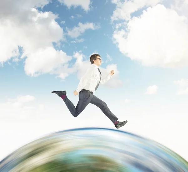 Uomo d'affari che corre sul globo con il cielo — Foto Stock